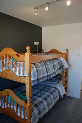 a bedroom with a wooden bunk bed with a plaid blanket at Tywyn Beach House in Tywyn