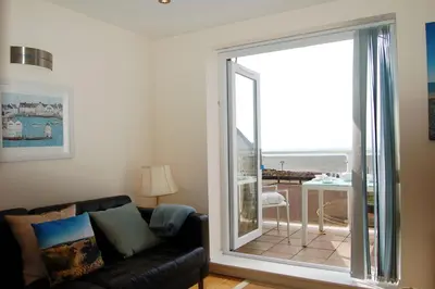 a living room with a couch and a sliding glass door at Sunset Bay Beach House in Tywyn in Tywyn