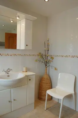 a bathroom with a sink and a vase with flowers at Sunset Bay Beach House in Tywyn in Tywyn