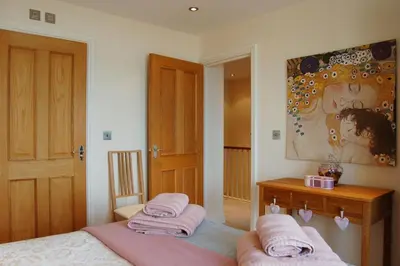 a bedroom with two beds and a table with towels at Sunset Bay Beach House in Tywyn in Tywyn