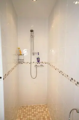 a bathroom with a shower and a tiled floor at Sunset Bay Beach House in Tywyn in Tywyn