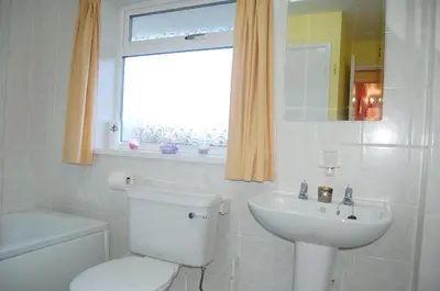 a bathroom with a toilet and a sink and a window at Wulfrun in Tywyn