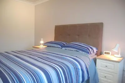 a bedroom with a bed and a nightstand with two lamps at Wulfrun in Tywyn