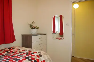 a bedroom with a bed and a dresser and a mirror at Wulfrun in Tywyn