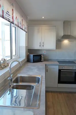 a kitchen with a sink and a microwave at Sunny Side Up Beach House in Tywyn in Tywyn
