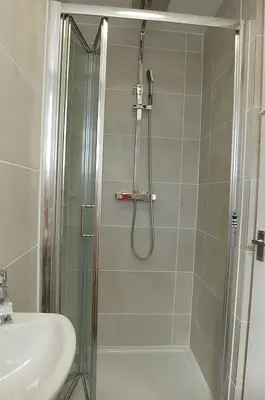 a shower with a glass door next to a sink at Sunny Side Up Beach House in Tywyn in Tywyn
