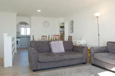 a living room with a couch and a kitchen at Sunny Side Up Beach House in Tywyn in Tywyn