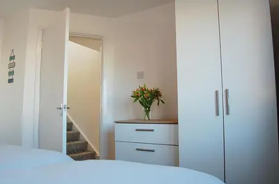a bedroom with a dresser and a vase of flowers at Sunny Side Up Beach House in Tywyn in Tywyn