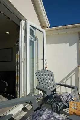 a rocking chair sitting on the balcony of a house at Sunny Side Up Beach House in Tywyn in Tywyn