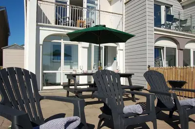 a patio with three chairs and a table with an umbrella at Sunny Side Up Beach House in Tywyn in Tywyn