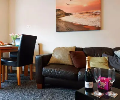 a living room with a couch and a table with wine glasses at Swn Y Tonnau in Tywyn