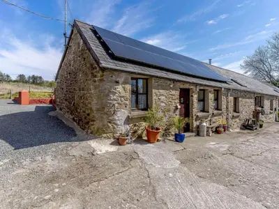 a stone house with solar panels on the roof at 1 Bed in Llanybydder oc-81354 in Llanwenog