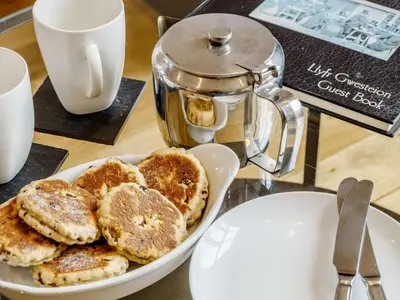 a plate of pancakes on a table with a kettle at 2 Bed in Brecon oc-bn100 in Cray