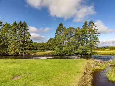 a river in a field with trees in the background at 4 Bed in Bala oc-75288 in Llandderfel