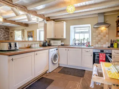 a kitchen with white cabinets and a washer and dryer at 2 Bed in Llanfihangel-nant-Bran BN200 in Llanfihangel-Nant-Brân