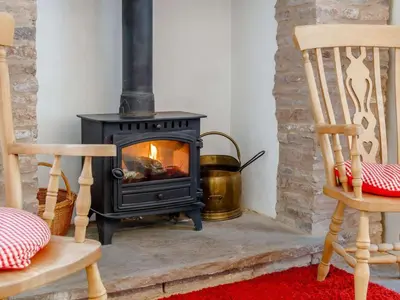 a wood stove in a living room with two chairs at 3 Bed in Brecon oc-bn331 in Cathedine