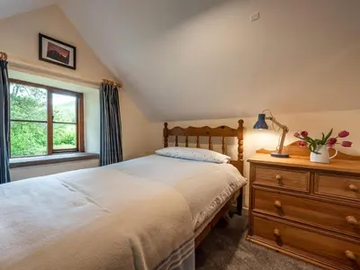 a bedroom with a bed and a dresser and a window at 4 Bed in Hereford oc-86497 in Llanveynoe