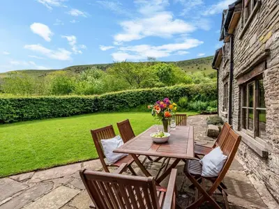 a wooden table and chairs on a patio at 4 Bed in Hereford oc-86497 in Llanveynoe