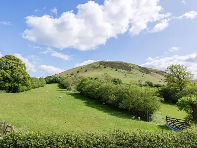 a grassy field with a hill in the background at 4 Bed in Llandinam oc-51651 in Llandinam