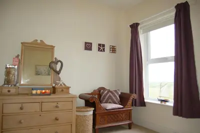 a room with a dresser and a mirror and a chair at Cadair View Family Holiday Home in Tywyn