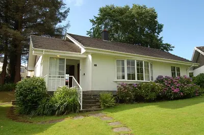 a small white house with a porch and flowers at Hafan Y Talgarth bungalow at Plas Talgarth resort in Pennal