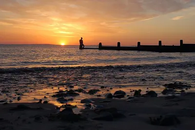a person standing on the beach watching the sunset at Idris View Family Holiday Home in Tywyn