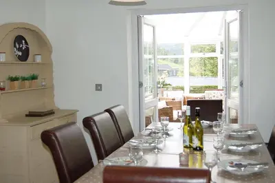 a dining room with a table with wine bottles and chairs at Glan yr Afon in Dolgellau in Dolgellau