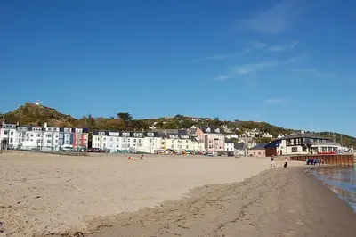 a beach with people walking on the sand and buildings at Glan yr Afon in Dolgellau in Dolgellau