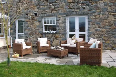 a group of wicker chairs and tables on a patio at Glan yr Afon in Dolgellau in Dolgellau