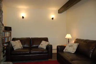 a living room with a brown leather couch and a lamp at Henborth Mawr Cottage in Talybont in Talybont