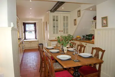 a dining room with a table and chairs and a kitchen at Henborth Mawr Cottage in Talybont in Talybont