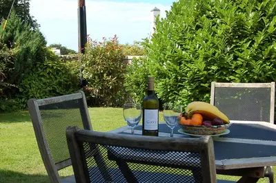 a table with a bottle of wine and a basket of fruit at Henborth Mawr Cottage in Talybont in Talybont