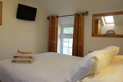 a bedroom with a white bed with a mirror and a window at Glyn Saron near Tywyn in Bryn-crug