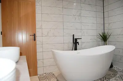 a white bath tub in a bathroom with a tile wall at Paradwys in Dolgellau in Dolgellau