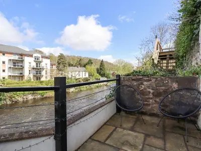 two chairs sitting on a balcony overlooking a river at No 9 On The Riverbank in Llangollen