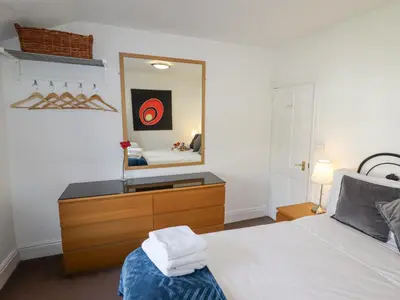 a bedroom with a bed with a dresser and a mirror at No 9 On The Riverbank in Llangollen
