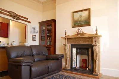 a leather couch in a living room with a fireplace at Sand Dune Apartment in Barmouth in Barmouth