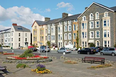 a parking lot with benches and buildings and cars at Sand Dune Apartment in Barmouth in Barmouth