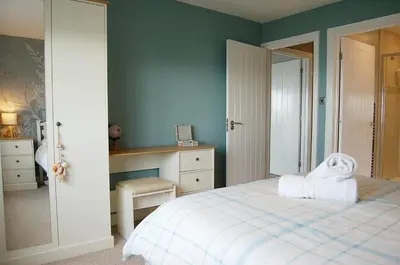 a bedroom with a white bed and a desk at Sound of the Sea, beach front Bungalow with hot tub, in Tywyn in Tywyn