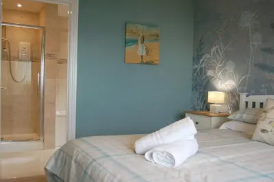 a bedroom with a bed with white pillows and a shower at Sound of the Sea, beach front Bungalow with hot tub, in Tywyn in Tywyn