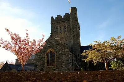 an old stone church with a tower with a tree at Caravan 309 Bryn Y Mor Beach Side Park in Tywyn