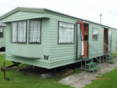 a green tiny house on display in a yard at Caravan 309 Bryn Y Mor Beach Side Park in Tywyn