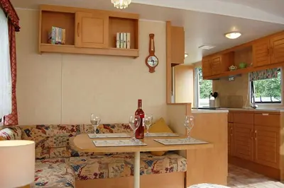 a living room with a couch and a table with wine glasses at Caravan B26 at The Woodlands in Tywyn