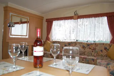 a bottle of wine sitting on a table with wine glasses at Caravan B26 at The Woodlands in Tywyn