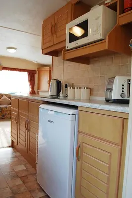 a kitchen with a white refrigerator and a microwave at Caravan B26 at The Woodlands in Tywyn