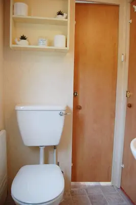 a bathroom with a white toilet and a door at Caravan B26 at The Woodlands in Tywyn
