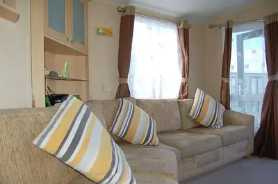 a living room with a couch with pillows on it at Caravan 251 Bryn Y Mor Beach Side Park in Tywyn