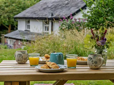 a wooden table with plates of bread and glasses of orange juice at 1 Bed in Brecon oc-bn157 in Llangorse