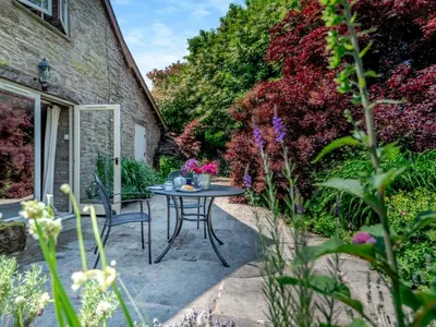 a patio with a table and chairs in a garden at 1 Bed in Clyro BN290 in Clyro