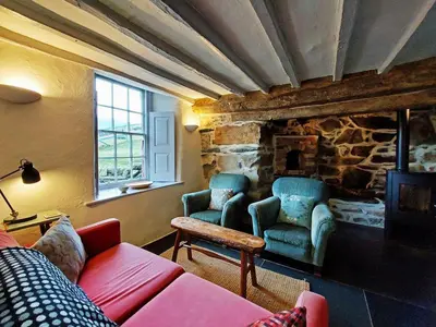 a living room with a couch and a stone fireplace at CaeEinion Cottage a Georgeous Rural Retreat Nr Dolgellau in Dolgellau